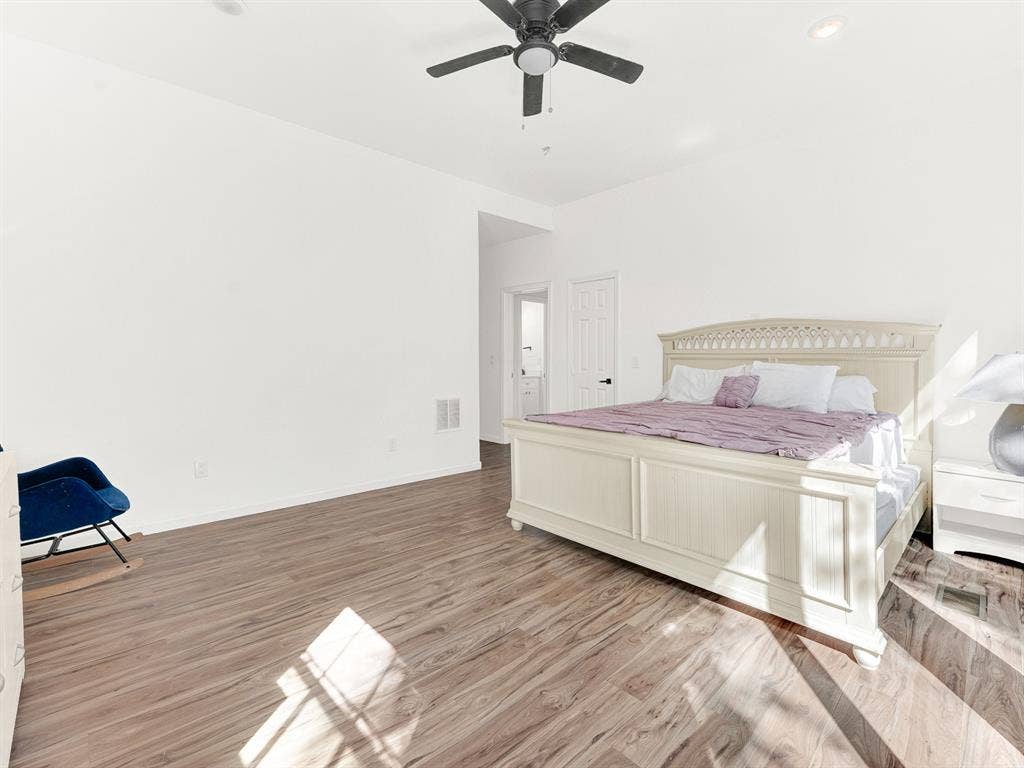 Spacious room featuring wood-finish flooring, high ceilings, recessed lighting, and a ceiling fan