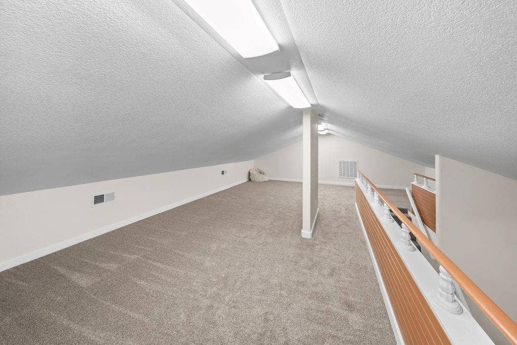 15993 Big Oak Bay Road, Tyler, TX 75707 Finished loft space featuring angled ceilings, wall-to-wall carpeting, flush-mount lighting, and a white balustrade with a wooden handrail