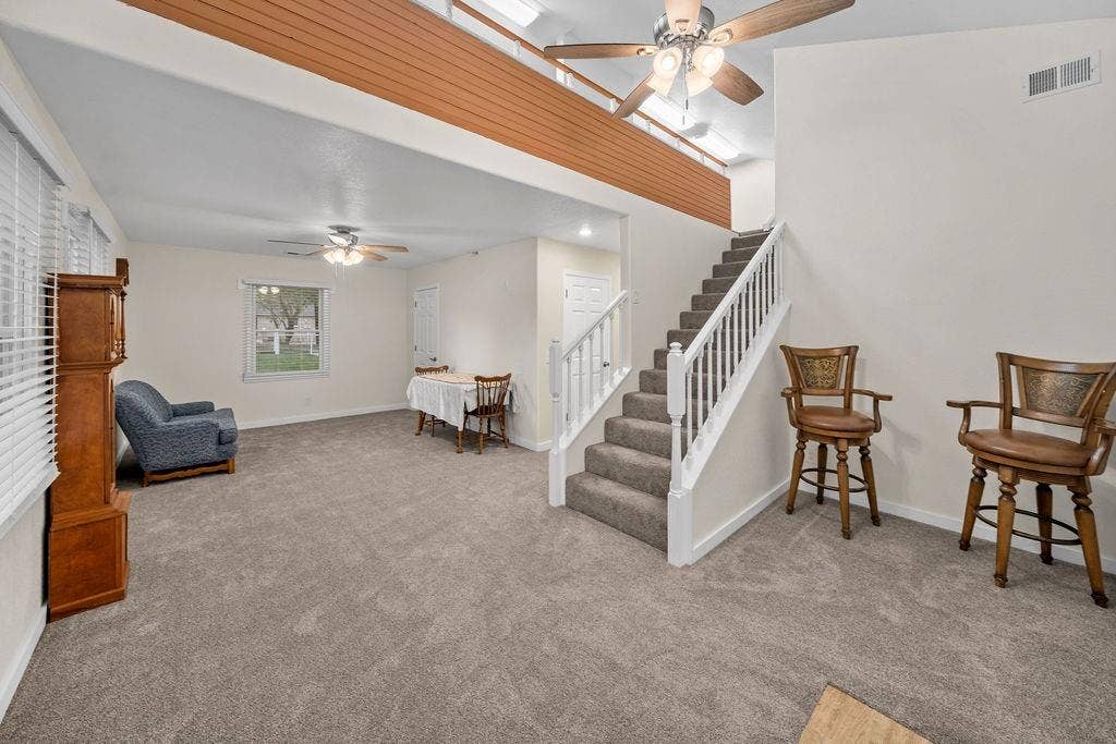 15993 Big Oak Bay Road, Tyler, TX 75707 Vaulted ceilings, carpeted staircase with white balusters, wood-finish horizontal trim detail, dual ceiling fans, and neutral wall tones