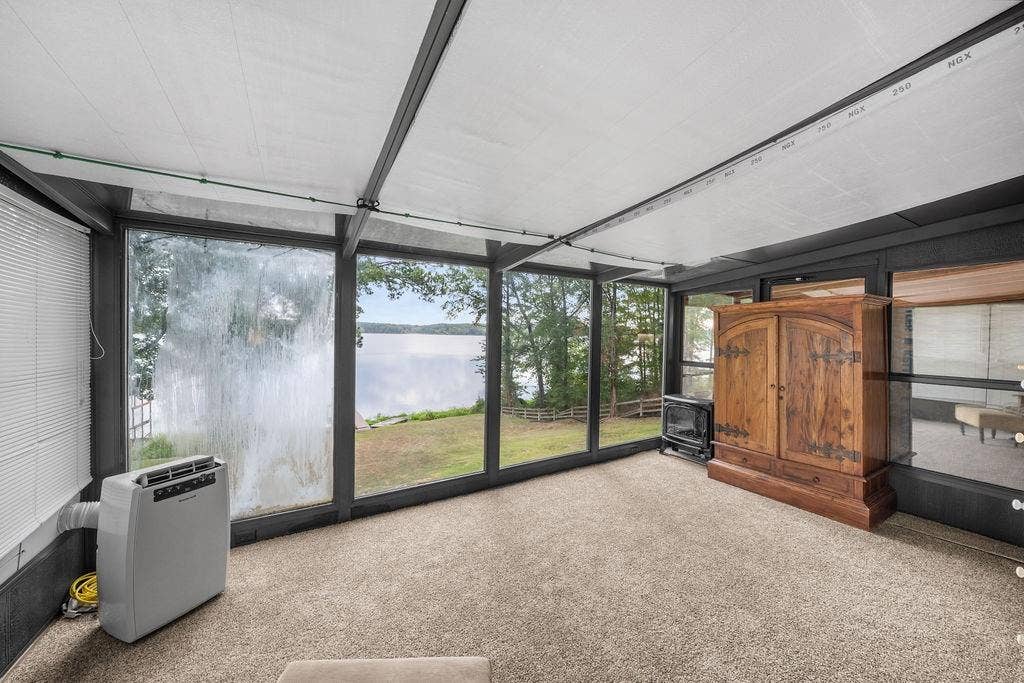 15993 Big Oak Bay Road, Tyler, TX 75707 Enclosed sunroom featuring expansive floor-to-ceiling windows, high-contrast dark structural framing, and a carpeted floor