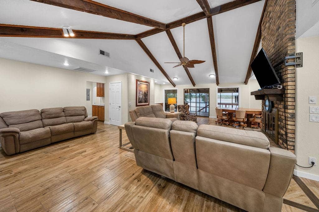 15993 Big Oak Bay Road, Tyler, TX 75707 Vaulted ceiling featuring exposed wood-finish beams, wood-finish tile flooring, full-height brick fireplace with a wood mantel, and sliding glass doors