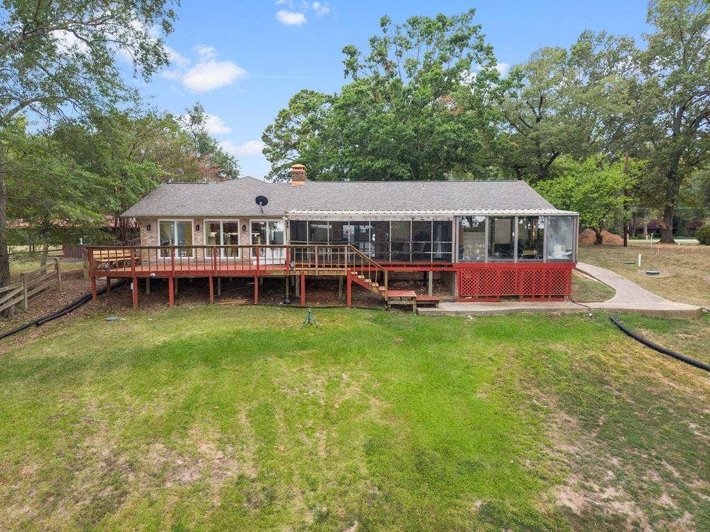 15993 Big Oak Bay Road, Tyler, TX 75707 Exterior of the property featuring a raised wooden deck, a screened-in porch, brick siding, a concrete walkway, and expansive grounds