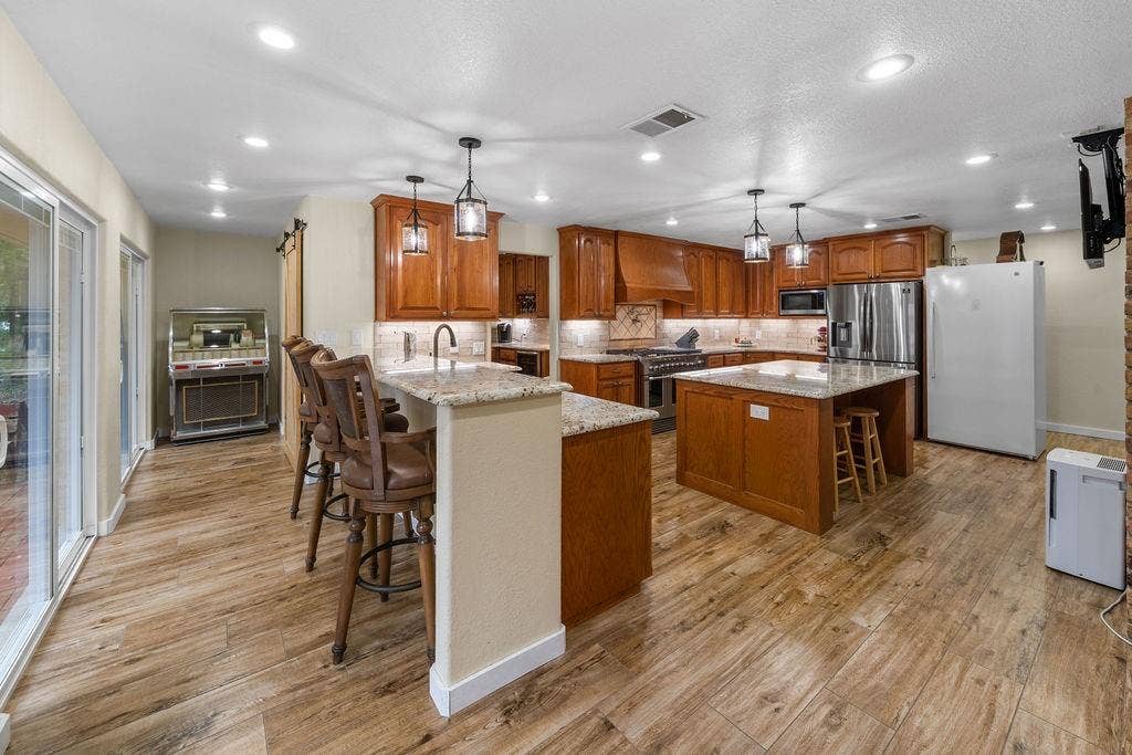 15993 Big Oak Bay Road, Tyler, TX 75707 Kitchen featuring custom wood cabinetry, stone countertops, central island, wood-finish flooring, and pendant lighting
