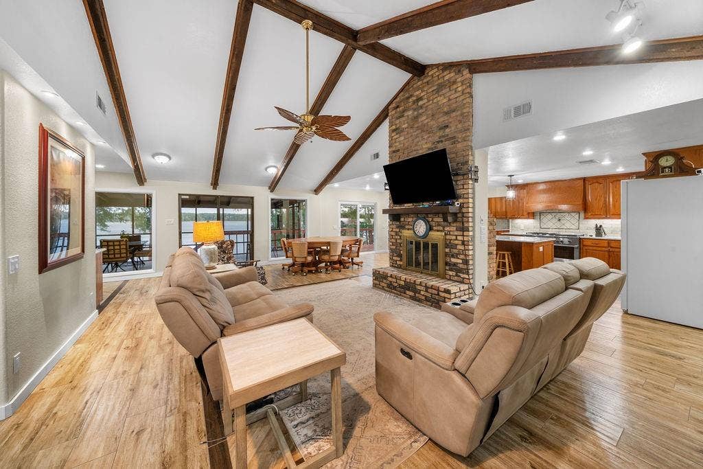 15993 Big Oak Bay Road, Tyler, TX 75707 Vaulted ceiling with exposed wood beams, brick fireplace featuring a wooden mantel, and wood-finish flooring