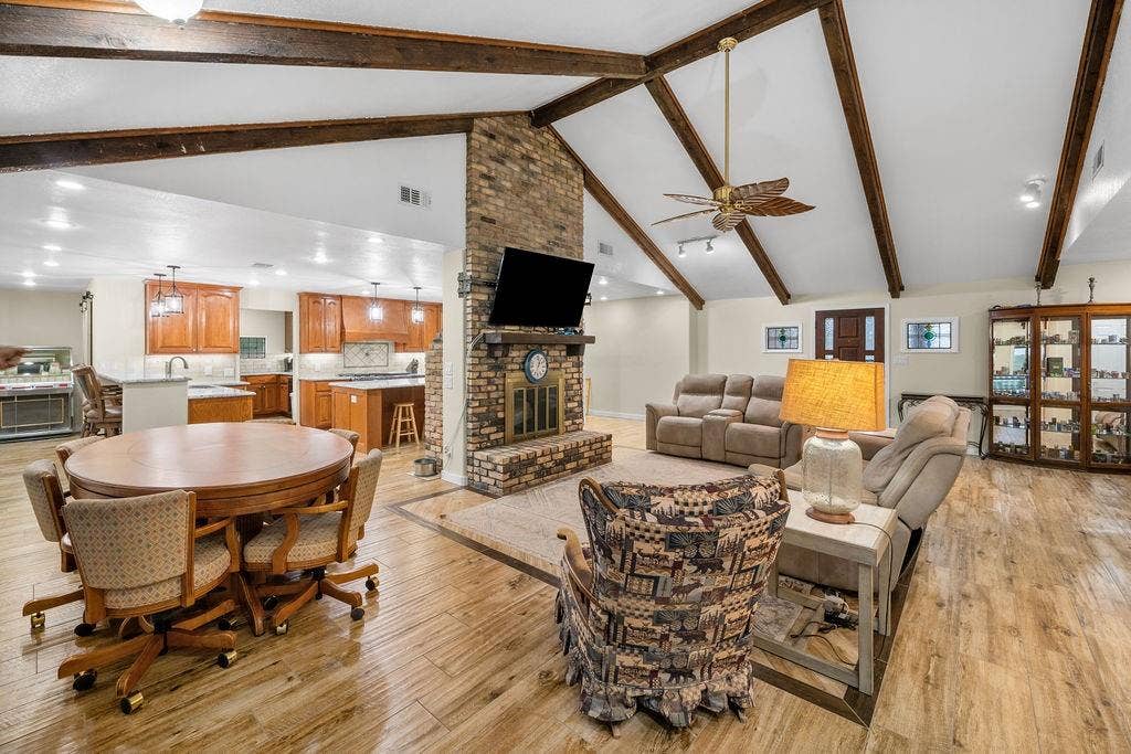 15993 Big Oak Bay Road, Tyler, TX 75707 Vaulted ceiling with exposed wood beams, full-height masonry fireplace, and wood-finish flooring