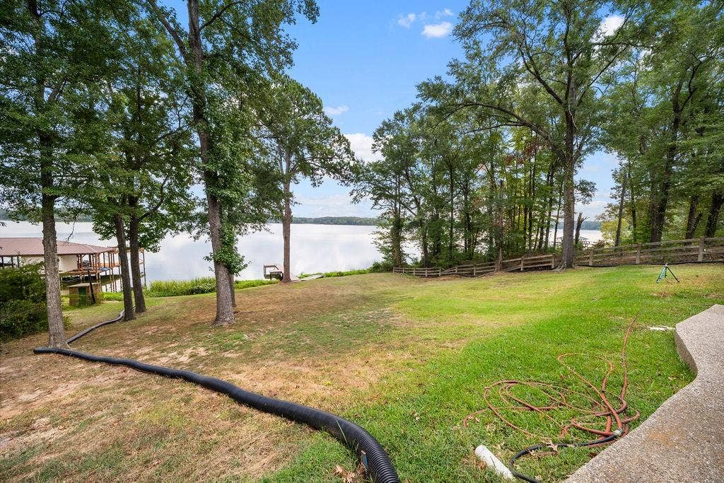 15993 Big Oak Bay Road, Tyler, TX 75707 Waterfront lot featuring a grass lawn, mature trees, and wooden perimeter fencing