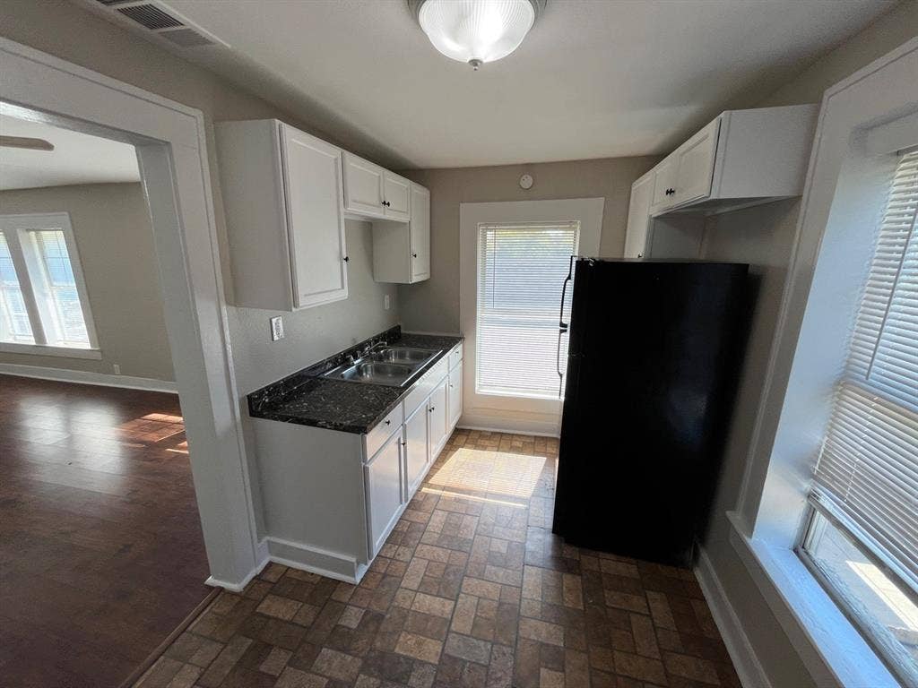 Kitchen featuring white cabinetry, dark stone-patterned countertops, a double-basin stainless steel sink, and mosaic-tiled flooring