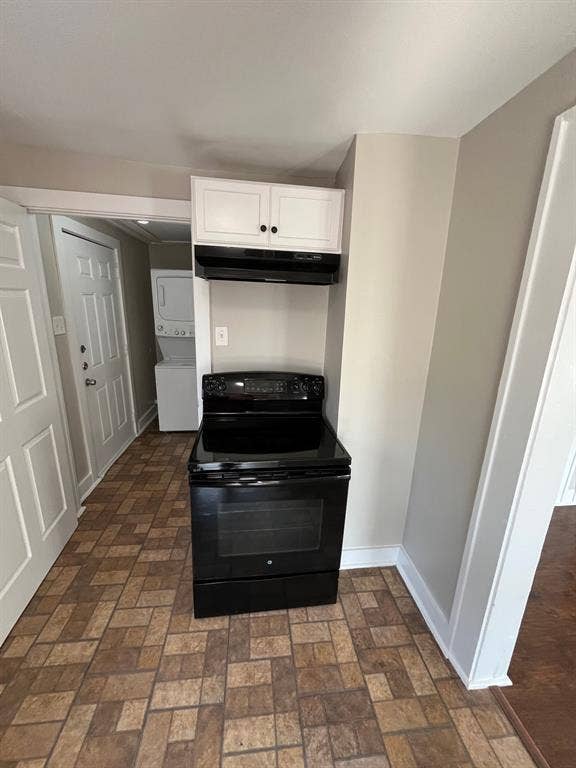 Kitchen area featuring a black electric range, a black range hood, and white upper cabinetry