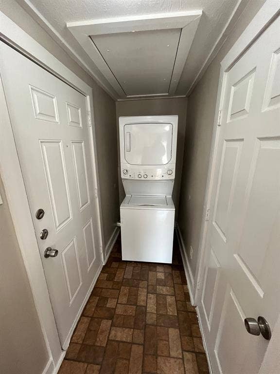 Laundry area featuring a stacked washer and dryer, tile flooring, and two white paneled doors