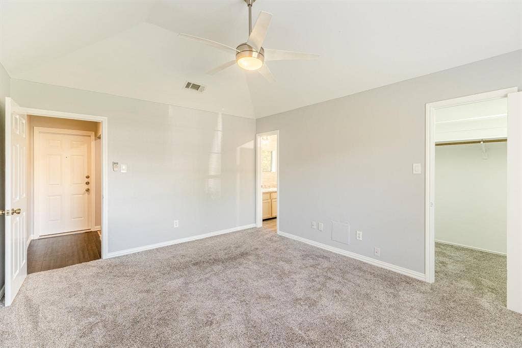 3618 Flagstone Avenue, Rowlett, TX 75088 Vaulted ceiling featuring a central brushed-nickel ceiling fan with integrated lighting, wall-to-wall carpeting, and a walk-in closet with built-in shelving
