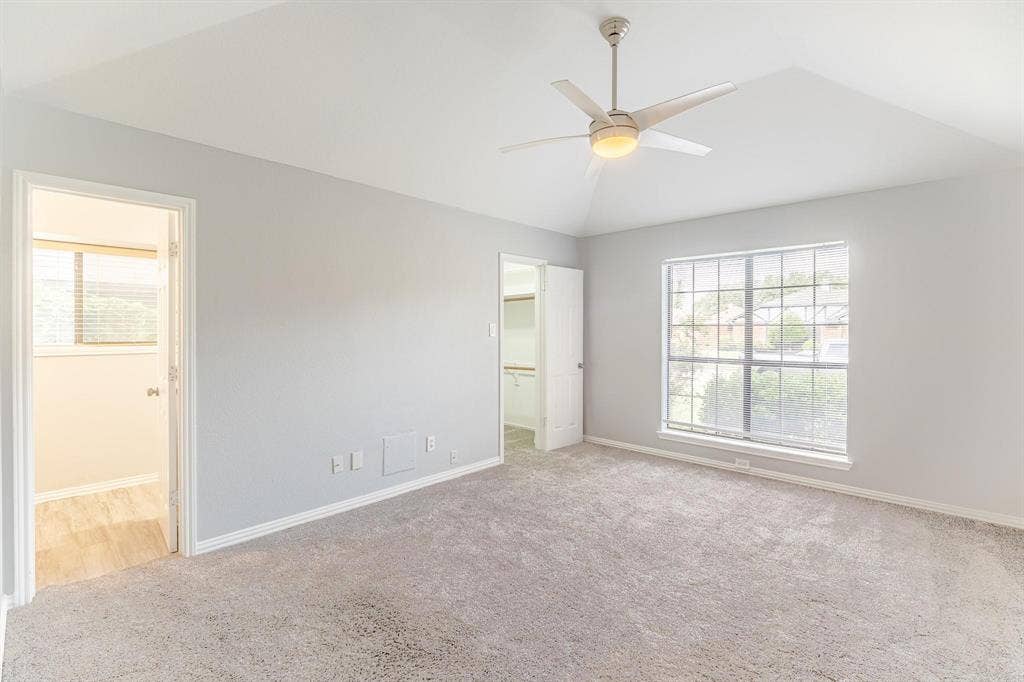3618 Flagstone Avenue, Rowlett, TX 75088 Vaulted ceiling with a central brushed-nickel ceiling fan, neutral wall-to-wall carpeting, and a multi-pane grid window