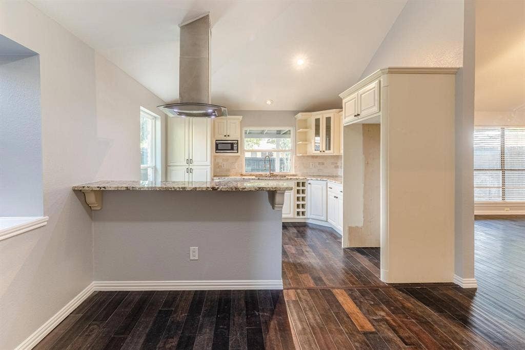 3618 Flagstone Avenue, Rowlett, TX 75088 Kitchen featuring stone countertops, white cabinetry, a built-in wine rack, stainless steel chimney-style range hood, and dark wood-finish flooring
