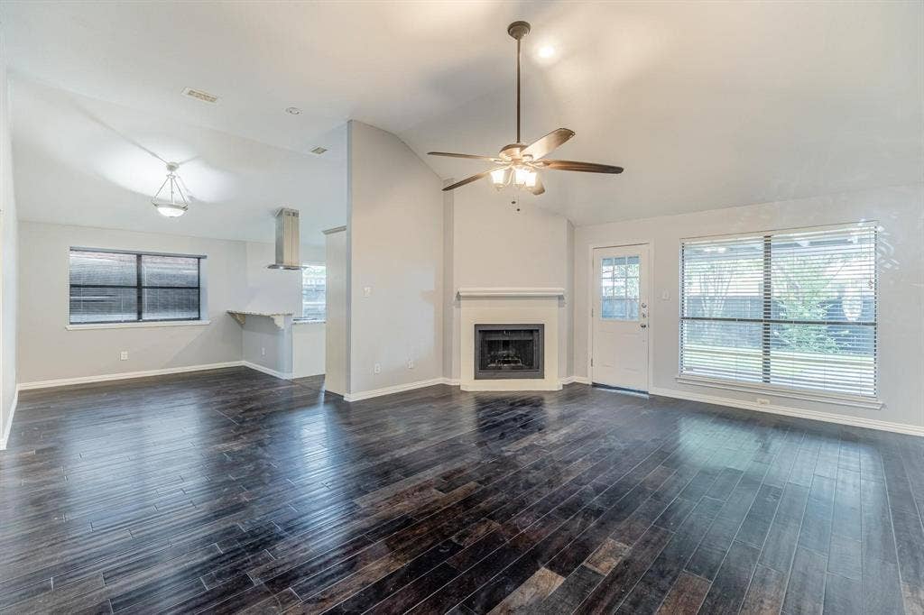 3618 Flagstone Avenue, Rowlett, TX 75088 Vaulted ceilings with a central ceiling fan, dark wood-finish flooring, corner fireplace with a mantel, and recessed lighting