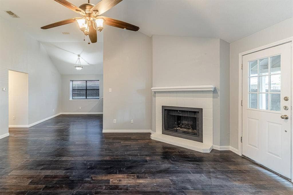 3618 Flagstone Avenue, Rowlett, TX 75088 Vaulted ceilings, wood-finish flooring, corner fireplace with white tile surround, ceiling fan, and multi-lite glass panel door