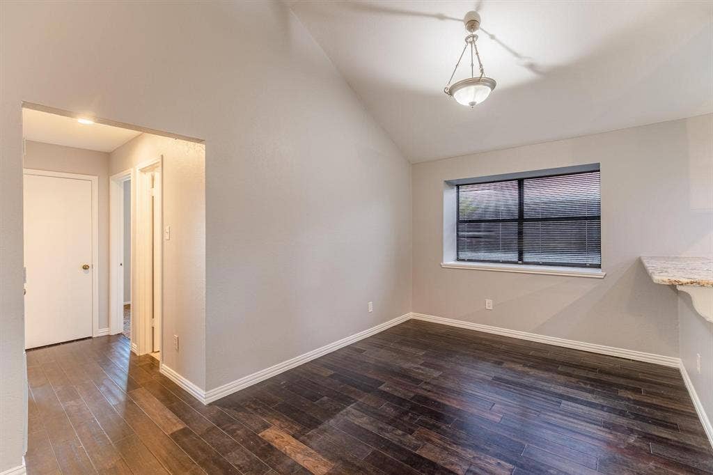 3618 Flagstone Avenue, Rowlett, TX 75088 Vaulted ceilings, wood-finish flooring, neutral wall color, hanging light fixture, and stone-finish countertop edge