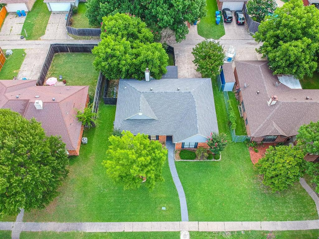3618 Flagstone Avenue, Rowlett, TX 75088 Aerial perspective featuring a brick exterior, gabled roof, concrete walkway, and mature trees on a level lot