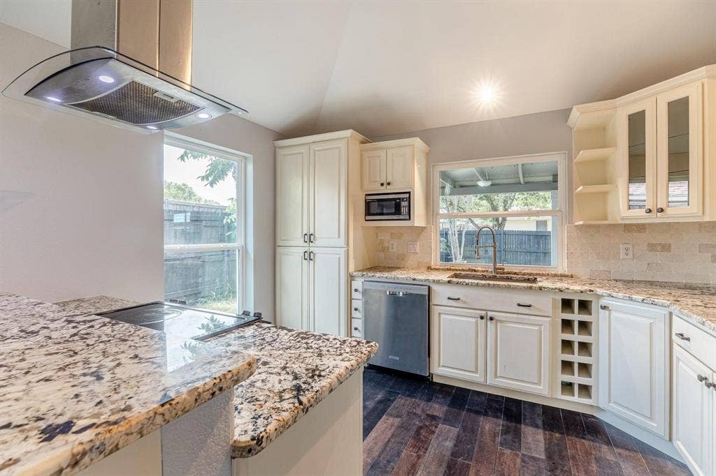 3618 Flagstone Avenue, Rowlett, TX 75088 Kitchen featuring custom off-white cabinetry, stone-surface countertops, built-in wine storage, stainless steel appliances, and wood-finish flooring
