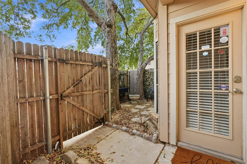 14333 Preston Road, #806, Dallas, TX 75254 Exterior area featuring a wooden privacy fence, concrete patio, stepping stone pathway, and mature trees