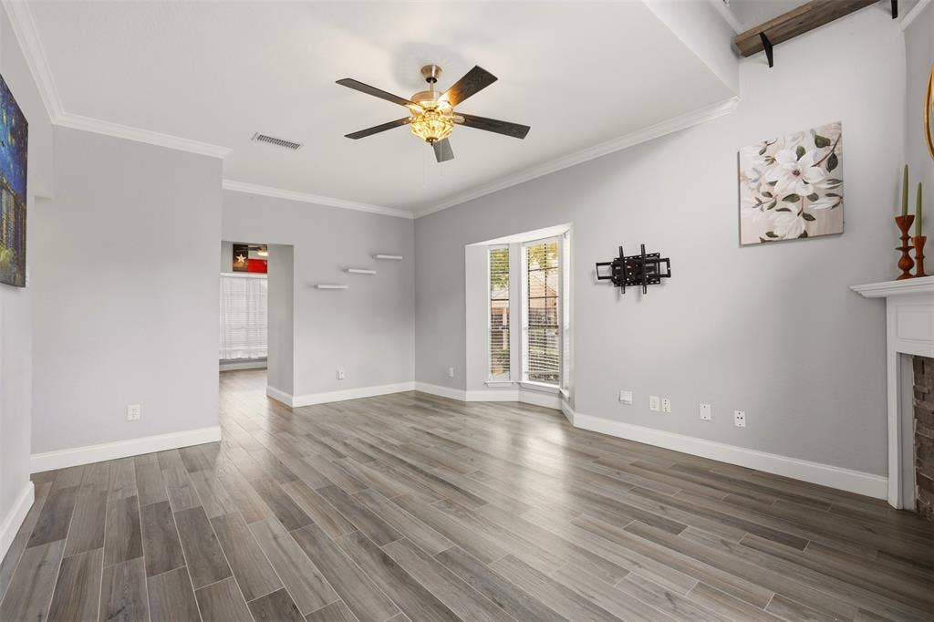 14333 Preston Road, #806, Dallas, TX 75254 Living area featuring wood-finish tile flooring, a recessed tray ceiling with a multi-blade ceiling fan, a bay window, and a hearth with a brick fireplace surround