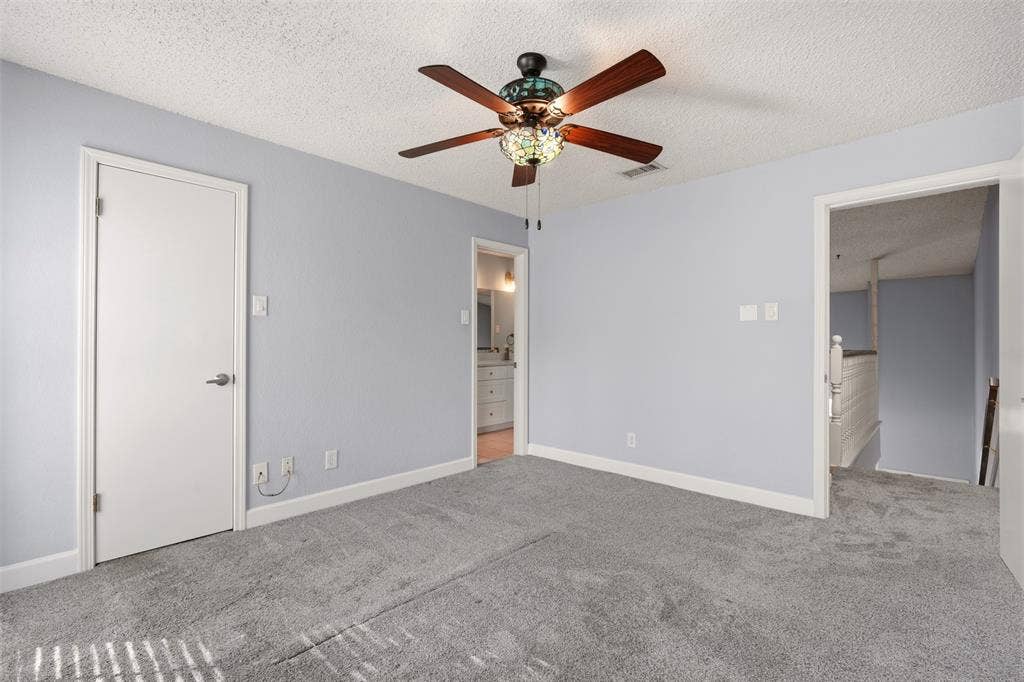 14333 Preston Road, #806, Dallas, TX 75254 Neutral-toned carpeting, ceiling fan with integrated stained-glass light fixture, and textured ceiling finish