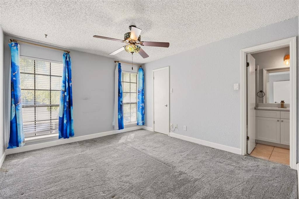 14333 Preston Road, #806, Dallas, TX 75254 Room featuring grey carpeting, two multi-pane windows, and a ceiling-mounted fan with integrated lighting