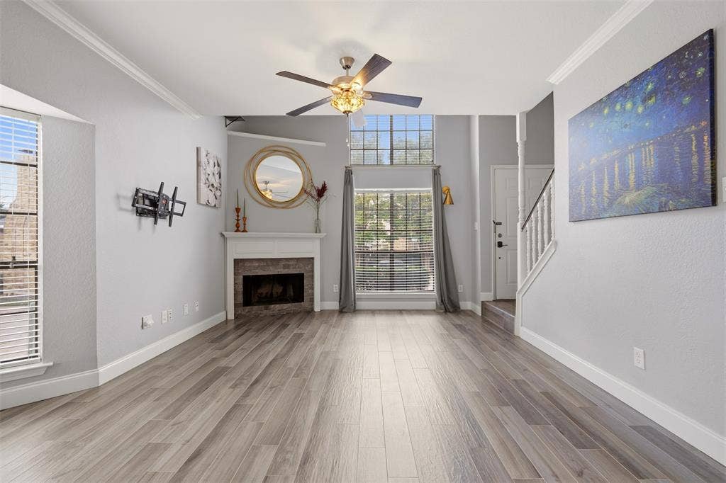 14333 Preston Road, #806, Dallas, TX 75254 Wood-finish flooring, fireplace with a tiled hearth, vaulted ceiling, multi-pane windows, and a ceiling fan