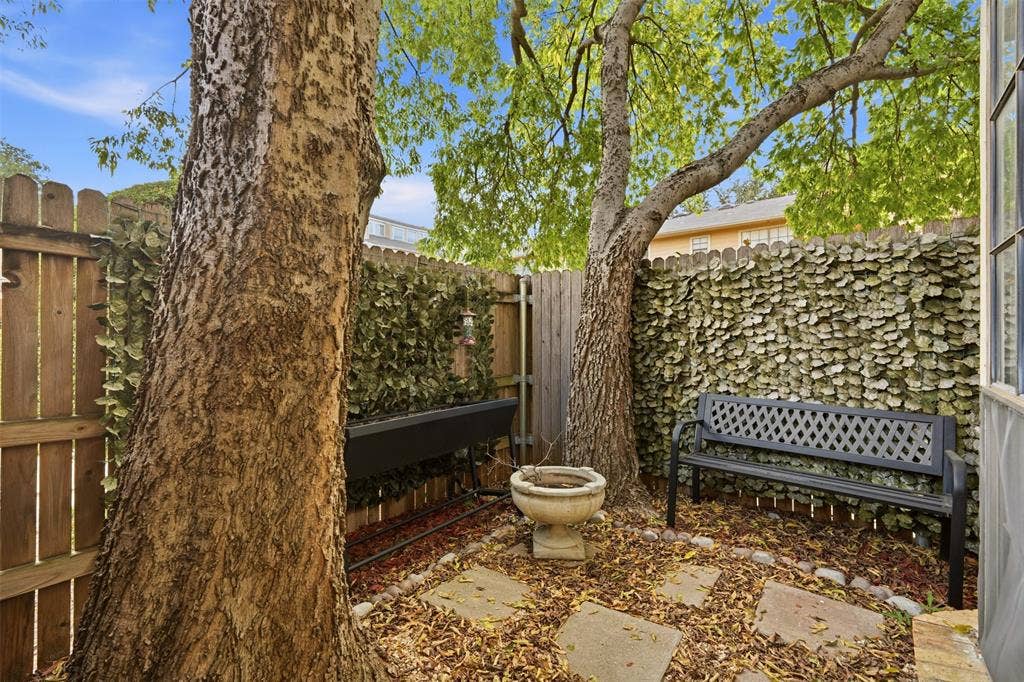 14333 Preston Road, #806, Dallas, TX 75254 Private outdoor courtyard featuring stone pavers, mature trees, and privacy wood fencing with integrated greenery