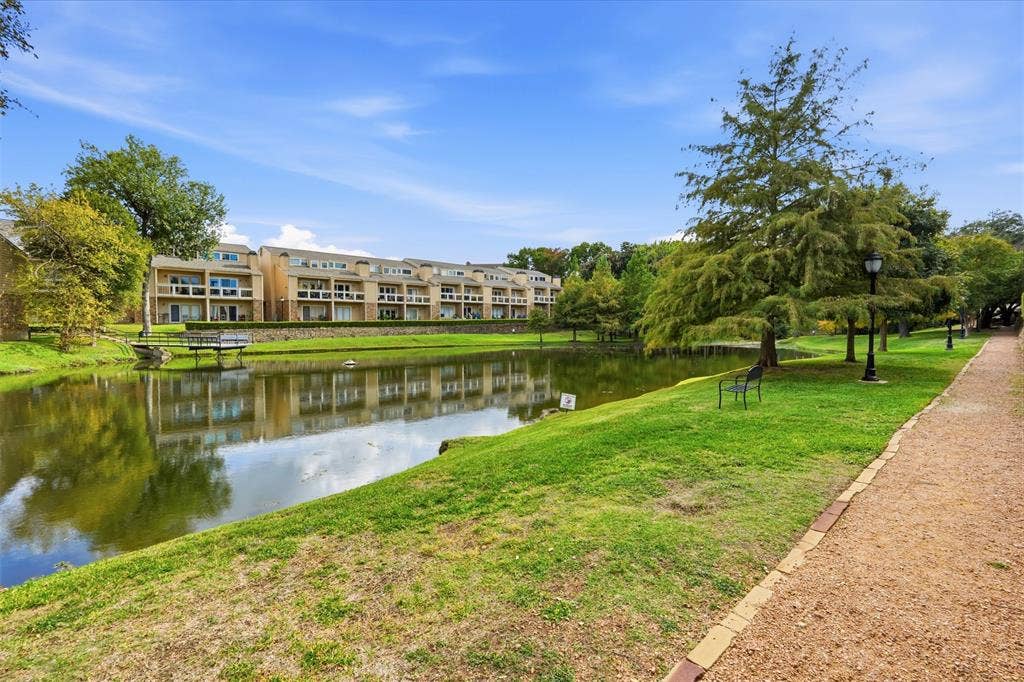 14333 Preston Road, #806, Dallas, TX 75254 Waterfront grounds featuring a landscaped pond, gravel pathway, mature trees, and stone retaining wall