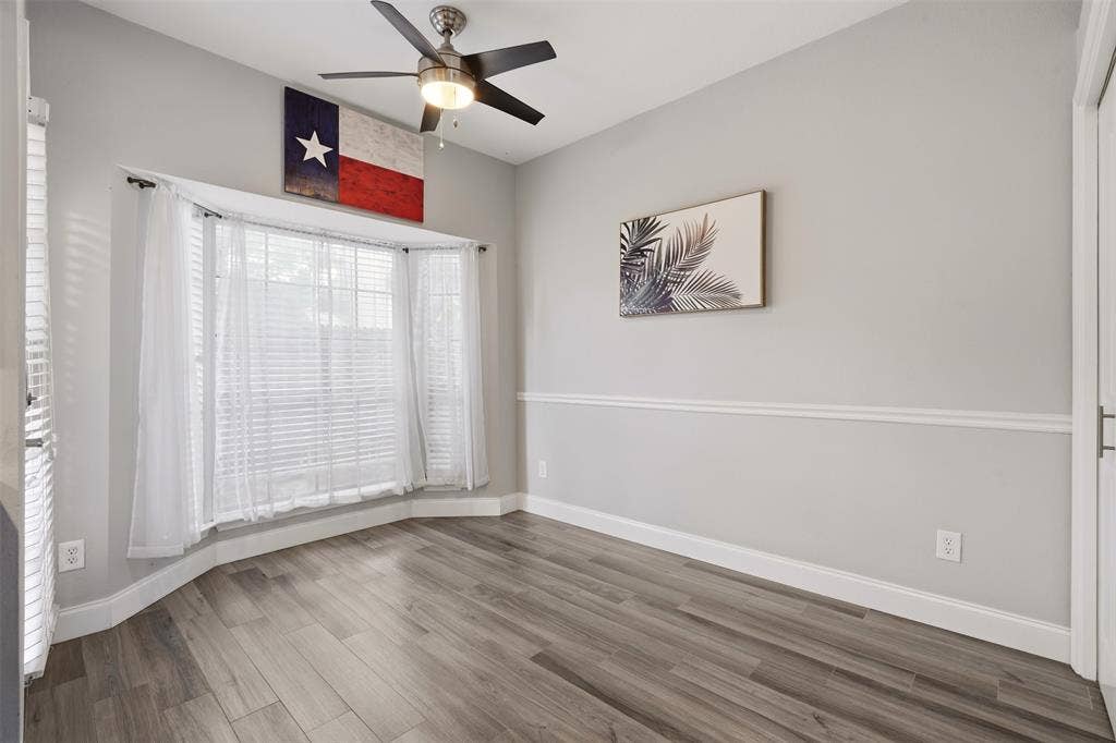 14333 Preston Road, #806, Dallas, TX 75254 Bay window, wood-finish flooring, chair rail molding, and a multi-blade ceiling fan with integrated lighting