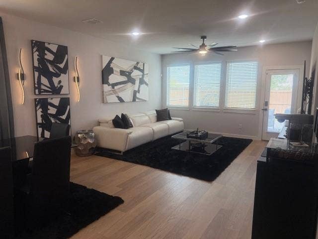 2416 Adenmore Lane, Forney, TX 75126 Open-concept interior featuring light-tone wood-finish flooring, recessed lighting, a modern ceiling fan, wall-mounted accent lighting, and a glass-paneled exterior door
