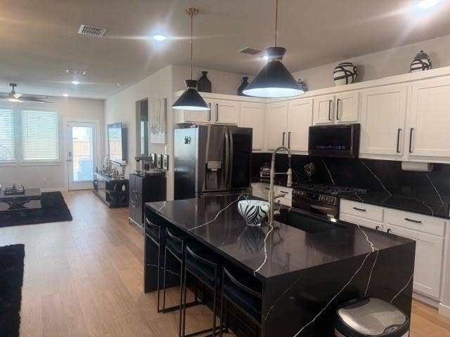 2416 Adenmore Lane, Forney, TX 75126 Kitchen featuring a central island with a contrasting stone-surface countertop, white shaker-style cabinetry, matte black hardware, recessed lighting, and wood-finish flooring