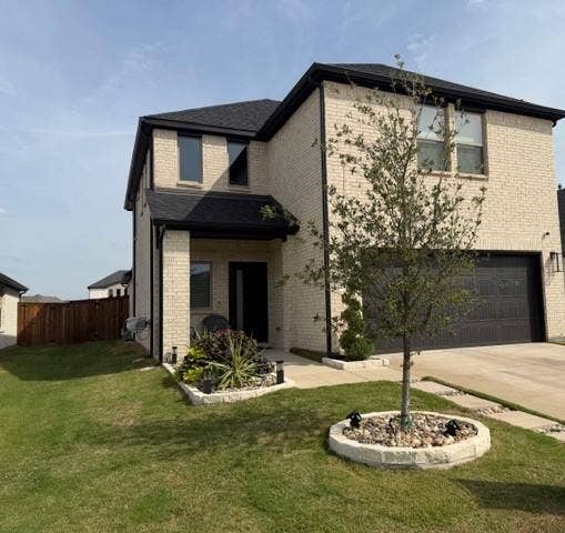 2416 Adenmore Lane, Forney, TX 75126 Two-story brick exterior featuring a dark shingle roof, attached garage, stone-lined landscaping beds, and a paved walkway