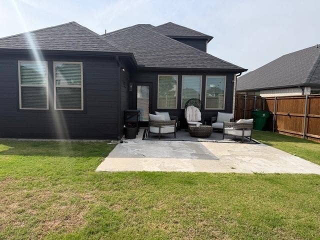 2416 Adenmore Lane, Forney, TX 75126 Exterior rear elevation featuring dark-toned siding, a multi-faceted roofline with asphalt shingles, a concrete patio, and a wood privacy fence