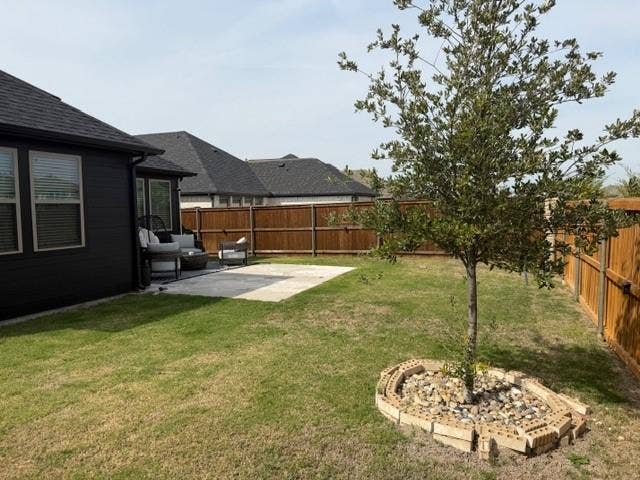 2416 Adenmore Lane, Forney, TX 75126 Backyard featuring a concrete patio, wood privacy fencing, grass lawn, and a tree with a decorative stone and brick base