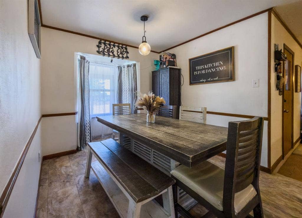 Dining area featuring a bay window, tile flooring, wood-toned chair rail molding, and a pendant light fixture