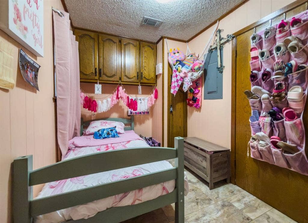 Bedroom featuring built-in wood-finish cabinetry, paneled wall construction, and tile flooring