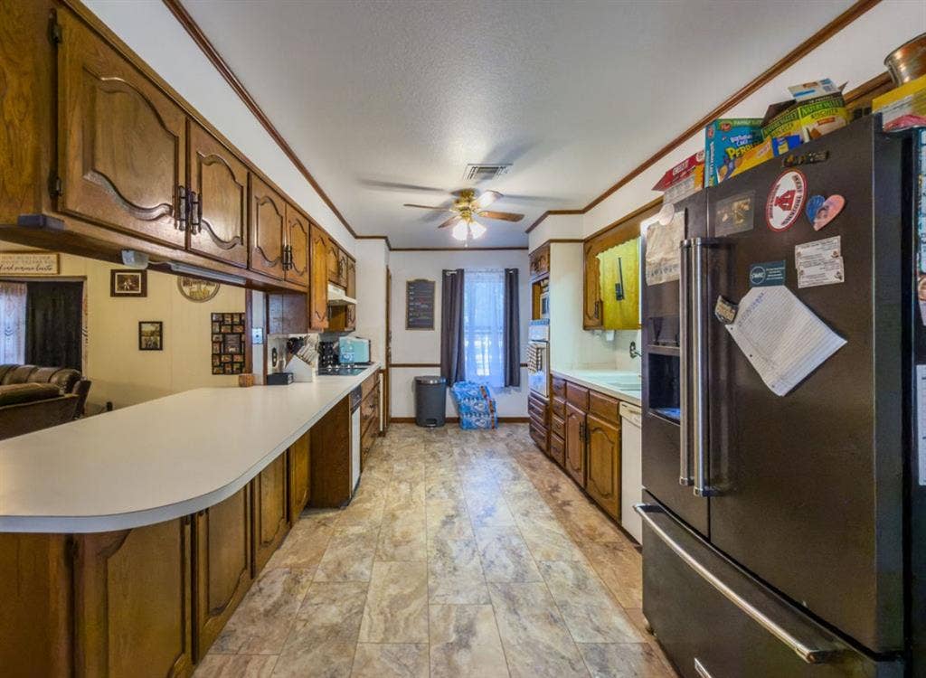 Kitchen featuring solid-wood cabinetry, extended laminate countertops, integrated cooktop, built-in wall oven, and resilient vinyl tile flooring