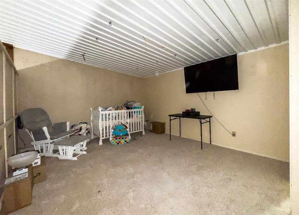 Interior space featuring neutral-toned walls and corrugated metal ceiling paneling