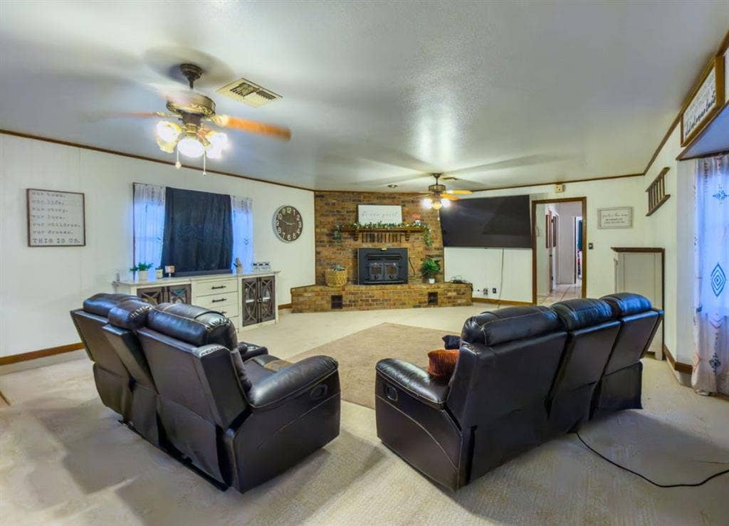 Brick fireplace with an integrated mantel and a recessed hearth, dual ceiling fans, and neutral wall finishes
