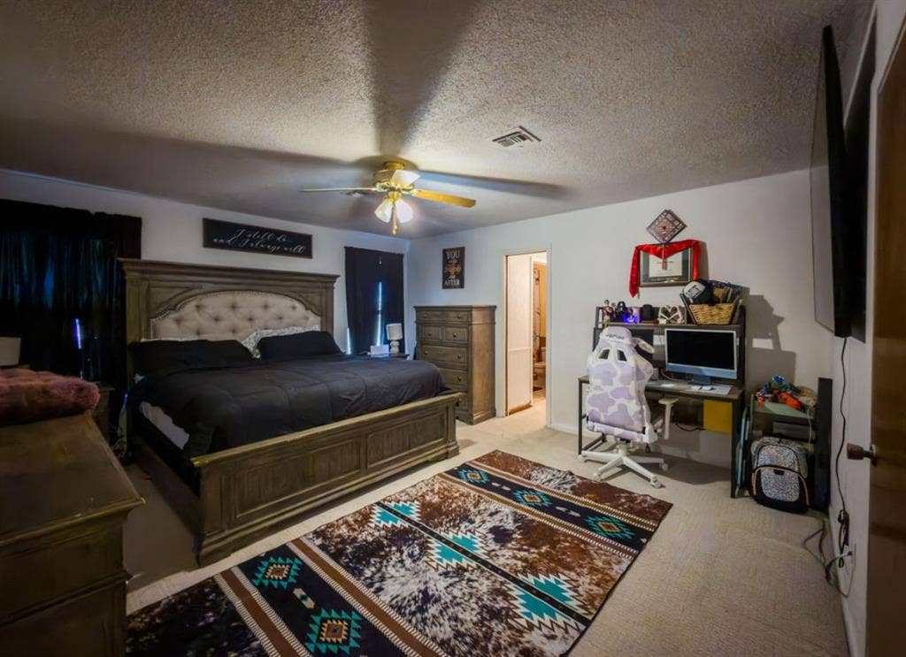 Spacious bedroom featuring neutral wall-to-wall carpeting and a central ceiling fan with integrated lighting