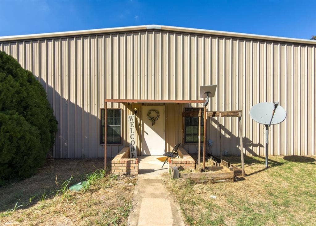 Metal-paneled exterior featuring a concrete walkway, brick-bordered entrance, and dual windows