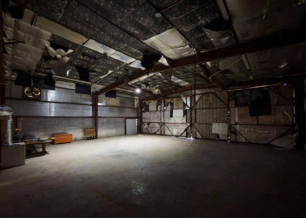 Expansive industrial space featuring a high-clearance steel frame, concrete flooring, and metallic insulation paneling