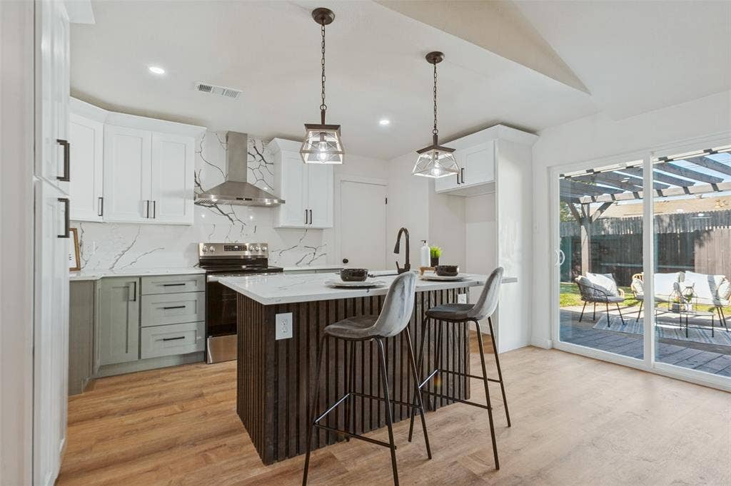 828 Melrose Drive, Richardson, TX 75234 Kitchen featuring shaker-style cabinetry, a central island with vertical wood detailing, a stone-patterned backsplash, stainless steel appliances, and wood-finish flooring
