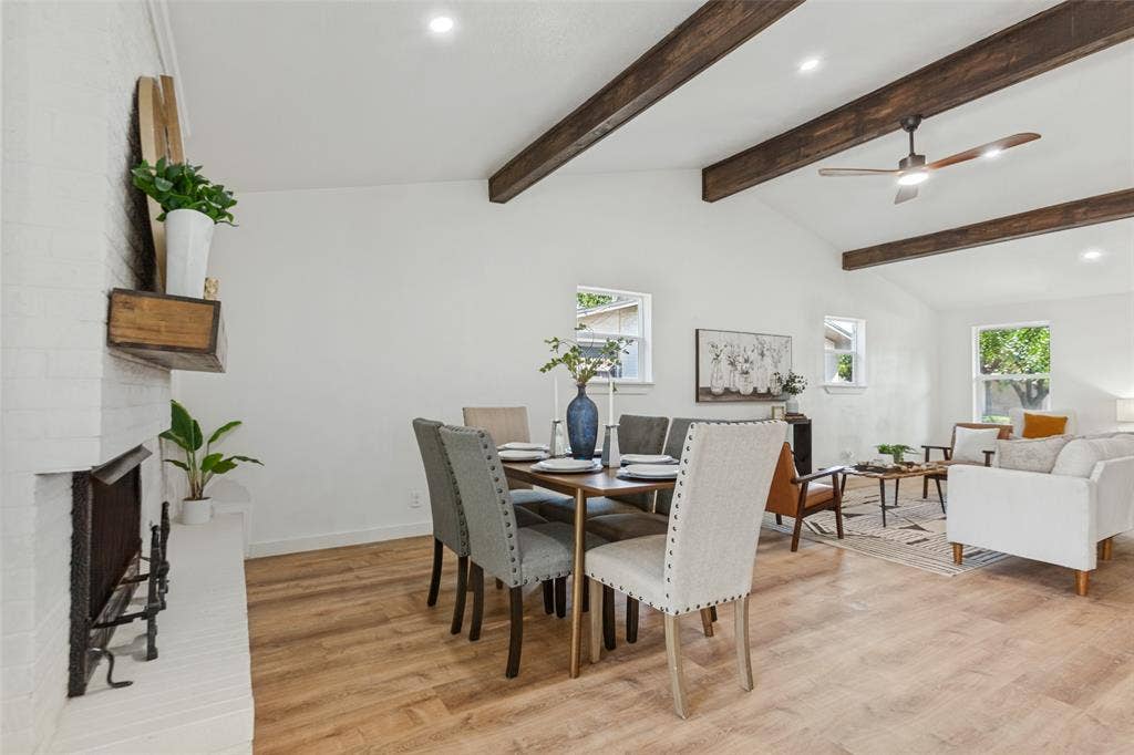 828 Melrose Drive, Richardson, TX 75234 Vaulted ceilings featuring exposed wood beams, white painted brick fireplace, and wood-finish flooring