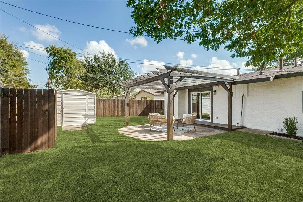 828 Melrose Drive, Richardson, TX 75234 Backyard featuring a wood pergola, paver patio, metal storage shed, and wood perimeter fencing