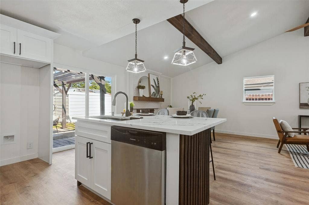 828 Melrose Drive, Richardson, TX 75234 Kitchen island featuring a stone-look countertop, integrated stainless steel dishwasher, and vertical wood-slat detailing