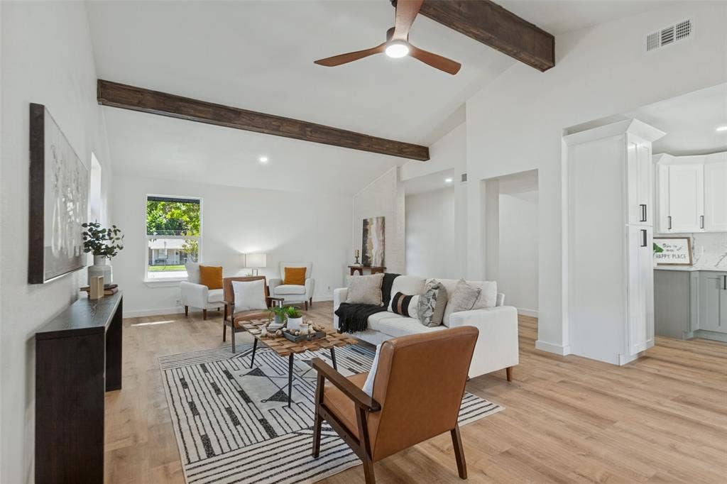 828 Melrose Drive, Richardson, TX 75234 Open-concept room featuring vaulted ceilings, dark wood-finish ceiling beams, wood-finish flooring, and a modern three-blade ceiling fan