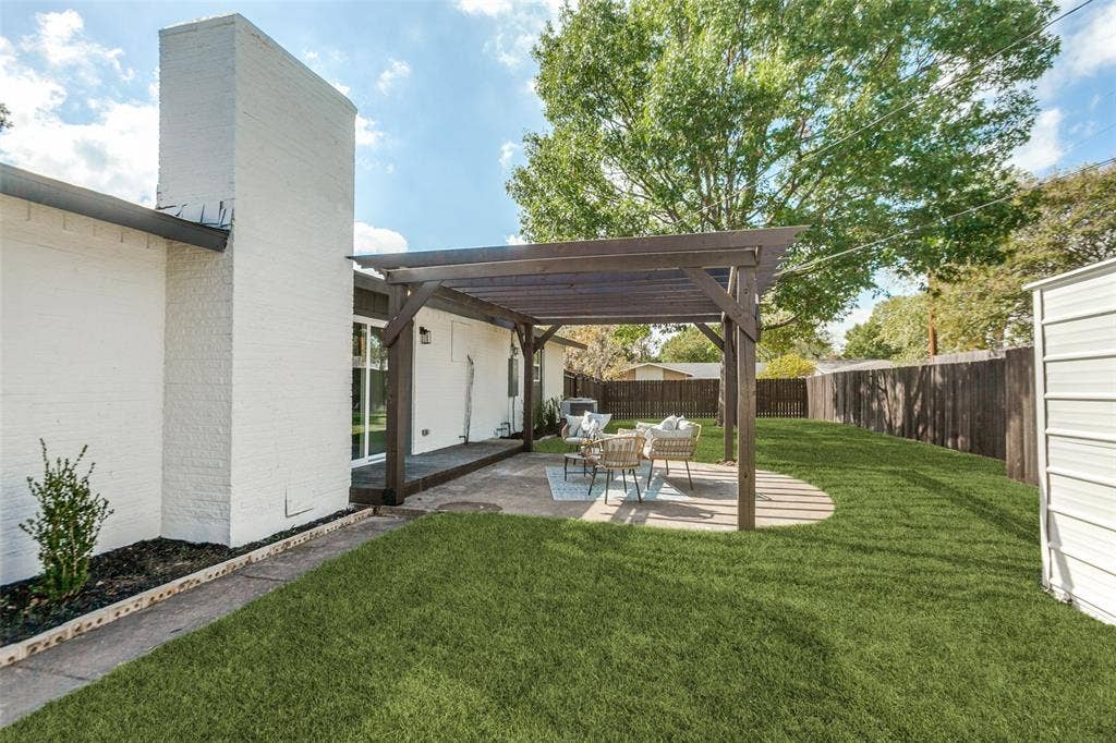 828 Melrose Drive, Richardson, TX 75234 Backyard featuring a concrete patio, a covered wooden pergola, a white masonry chimney, and a fenced-in lawn