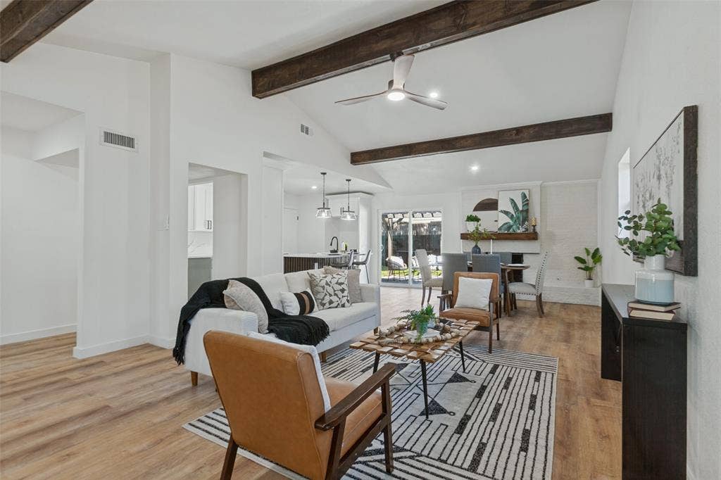 828 Melrose Drive, Richardson, TX 75234 Vaulted ceilings featuring exposed decorative beams, wood-finish flooring, a painted brick fireplace, and integrated ceiling fan