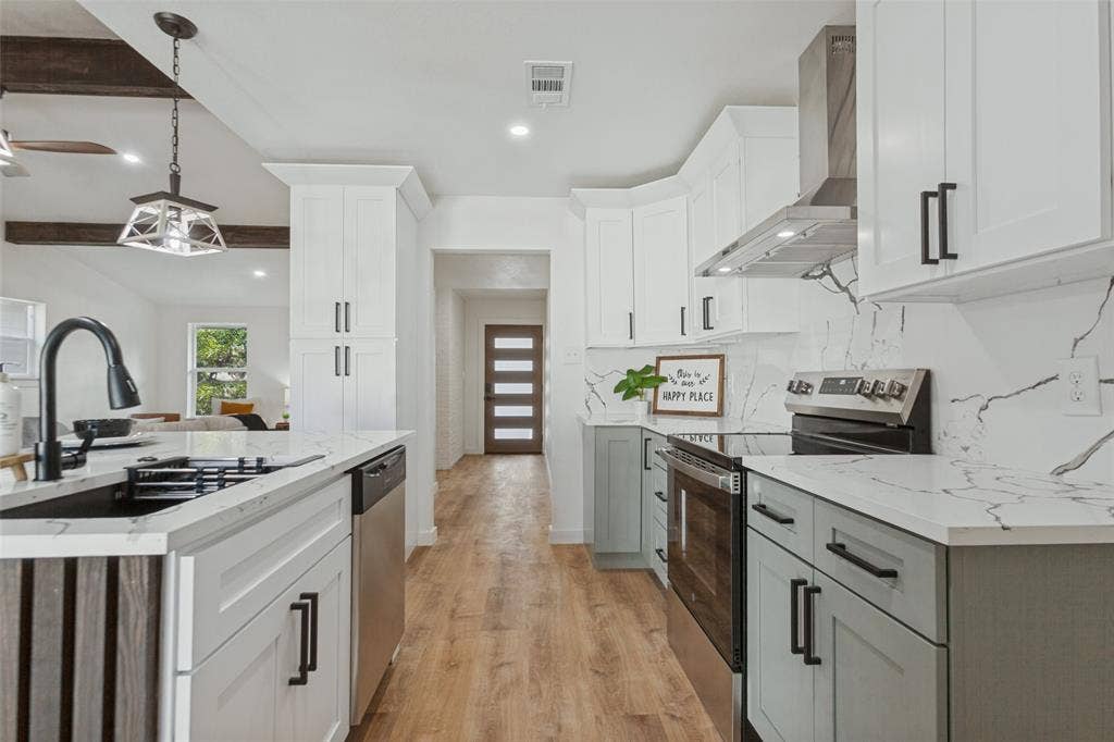828 Melrose Drive, Richardson, TX 75234 Kitchen featuring white shaker-style cabinetry, two-tone lower sage cabinetry, quartz countertops with veining, full-height decorative backsplash, and wood-finish flooring